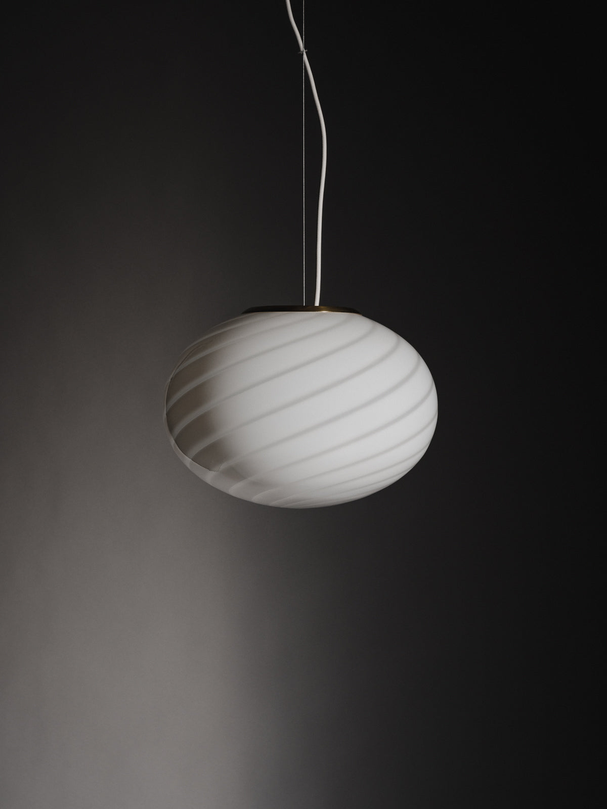 Sphere-shaped pendant lamp crafted from mouth-blown opaline glass. The design features a swirl pattern obtained using an original 1970s mould, specifically picked to give the lamp a clean expression. The piece includes a hand-casted fitting in solid brass. Handmade in Murano, Italy. Murano pendel loftslampe loftlampe Copenhagen Venice