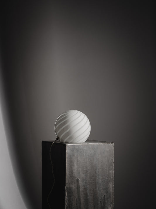 Sphere-shaped table lamp crafted from mouth-blown opaline glass. The design features a swirl pattern obtained using an original 1970s mould, specifically picked to give the lamp a clean expression. The piece includes hand-casted brass hardware.  Handmade in Murano, Italy Copenhagen Venice 