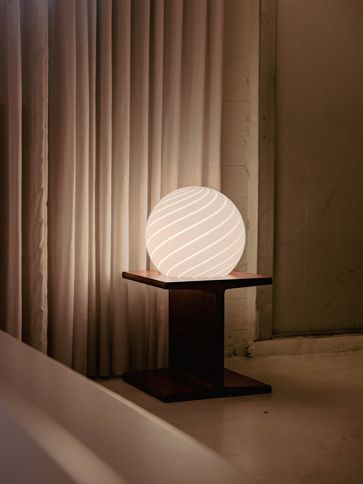 Sphere-shaped table lamp crafted from mouth-blown opaline glass. The design features a swirl pattern obtained using an original 1970s mould, specifically picked to give the lamp a clean expression. The piece includes hand-casted brass hardware.  Handmade in Murano, Italy Copenhagen Venice 